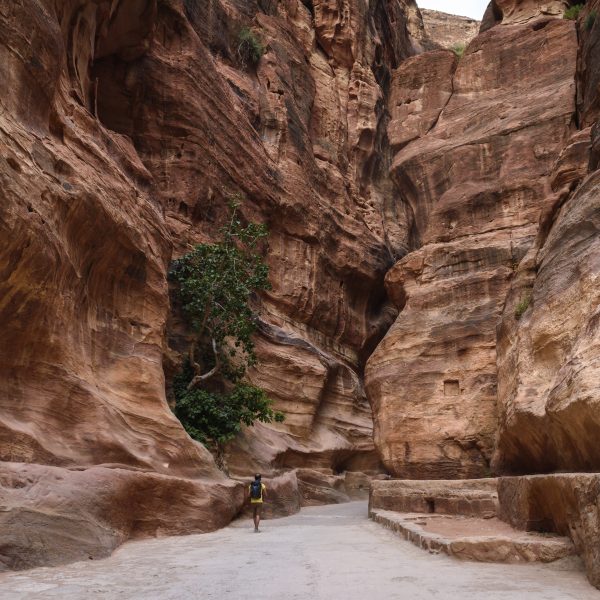 Man walking along path through rock formations at Petra, Jordan.